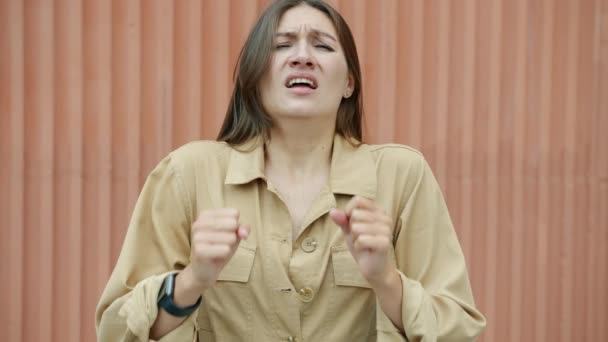 Retrato de la hermosa mujer joven estornudando y luego mirando a la cámara al aire libre con la pared en el fondo — Vídeos de Stock