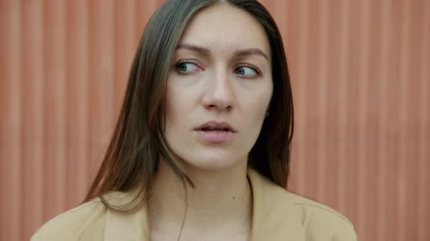 Slow motion close-up portrait of confused young woman rolling eyes standing outdoors — Stock Video