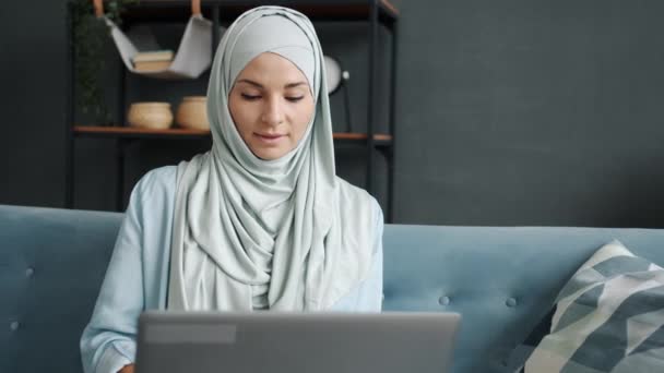 Portræt af forretningskvinde i hijab ved hjælp af bærbar computer, der arbejder indendørs hjemme og nyder fjernt job – Stock-video