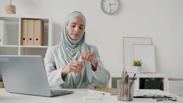 Mujer hijabi segura lavándose las manos con desinfectante y luego trabajando en la oficina durante la epidemia — Vídeos de Stock