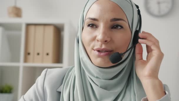 Retrato de la señora hijabi charlando con micrófono y auriculares hablando con el cliente en el centro de llamadas — Vídeos de Stock