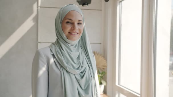 Retrato en cámara lenta de la hermosa joven musulmana usando hijab de pie en el interior de la cafetería — Vídeos de Stock