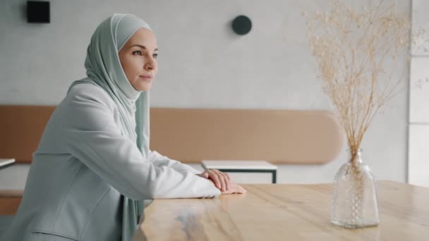 沉思的中东女人头戴头巾坐在咖啡桌旁的慢动作肖像 — 图库视频影像
