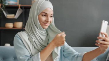 Orta Doğulu mütevazı bir kadının portresi akıllı telefon kamerasıyla evde tesettür takarak selfie çekiyor.