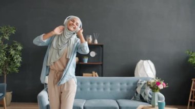 Evde dans eden, kulaklık takan güzel Müslüman kadının yavaş çekimde portresi.