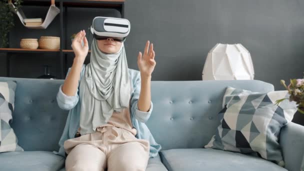 Slow motion portrait of modern muslimah using augmented reality glasses at home — Stock Video