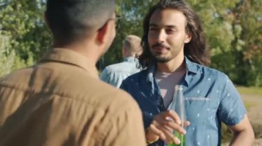 Mutlu yakışıklı erkeklerin portresi. Şişelerden içen ve parktaki açık hava partisinden keyif alan Araplar.