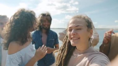 Sahilde dans eden, mutluluğu ifade eden ve kameraya bakan eşsiz genç arkadaşlar.
