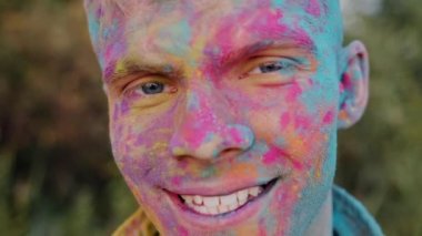 Holi kutlamasında gülümseyen renkli yüzlü çekici bir turistin yakın plan portresi.