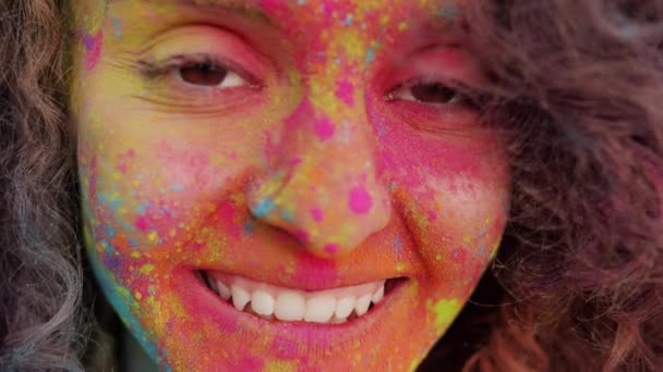 Close-up portret twórczej mieszane rasy kobieta z kolorowym twarzy patrząc w aparat fotograficzny po festiwalu Holi — Wideo stockowe