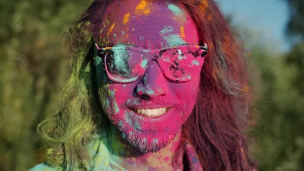 Close-up portrait of joyful bearded man smiling standing outdoors with face covered with paint enjoying Holi festival — Stock Video