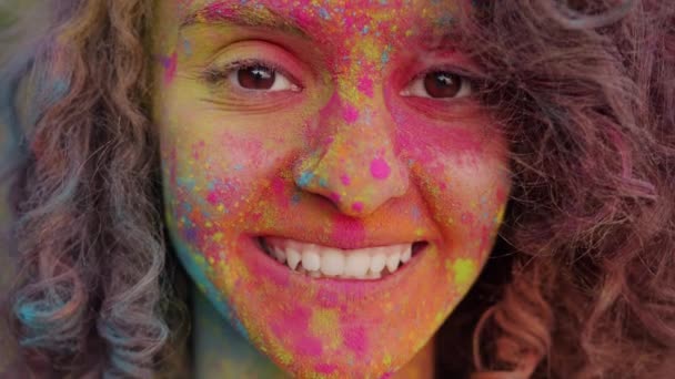 Close-up portrait of cheerful mixed race girl dirty with bright gulal paint smiling outdoors — Stock Video