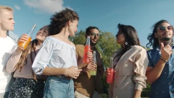 Portrait de jeunes heureux dansant tenant des bouteilles puis pointant vers la caméra et invitant à rejoindre la fête de la plage — Video