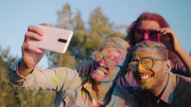 Estudantes do sexo masculino felizes desfrutando Holi festival tirando selfie com rostos coloridos usando câmera de telefone inteligente — Vídeo de Stock