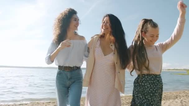 Αργή κίνηση πορτρέτο των χαριτωμένων νεαρών γυναικών που περπατούν στην παραλία αγκαλιάζοντας κουβέντα και χαμογελώντας — Αρχείο Βίντεο
