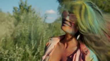 Holi festivalinde saçlarıyla oynayan, pudra boyasıyla kaplı neşeli Asyalı kızın ağır çekimde portresi.