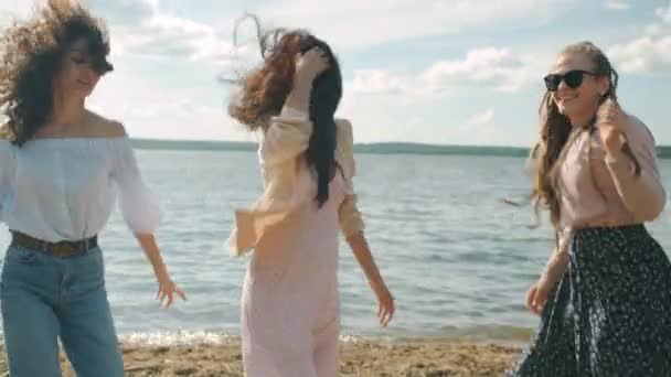 一緒に週末を楽しむ流行の夏の服を着てビーチで踊る女性の友人 — ストック動画