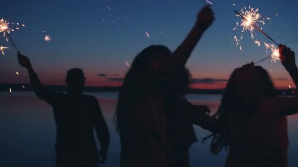 Langzame beweging van avontuurlijke jongeren die 's nachts plezier hebben met het dansen met sterretjes — Stockvideo