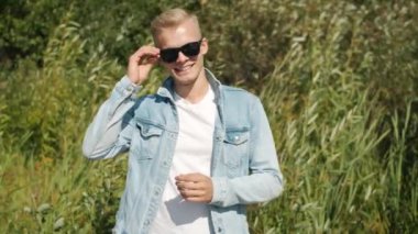 Yavaş çekimde neşeli sarışın adamın doğal fırın alanına karşı durup gülümsemesinin portresi.