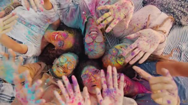 Top view portrait of cheerful youth with dirty faces stretching arms covered with gulal paint having fun at Holi party — Stock Video