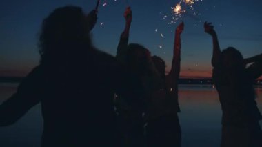 Tasasız milenyum kuşakları açık hava partisinde dans ediyor Bengal ışıkları sallıyor, birlikte eğleniyorlar.
