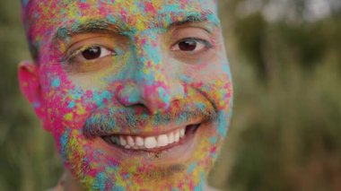 Holi partisinin dışında renkli yüzlü neşeli melez adamın yakın plan portresi.