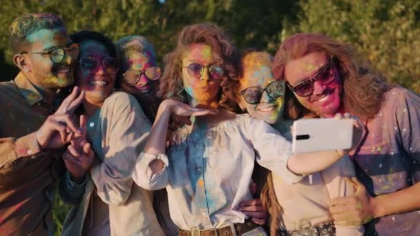 Zeitlupe lächelnder, mit heller Farbe verschmutzter junger Leute, die mit Smartphone-Kamera Selfies im Park machen — Stockvideo