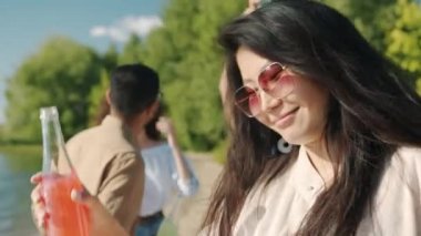 Plaj partisinde elinde içkiyle dışarıda dans eden neşeli Asyalı kadının yavaş çekim portresi.