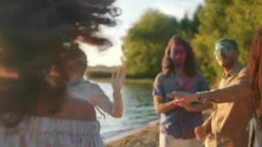 Holi festivali kutlamaları sırasında sahilde dans eden parlak boyayla kirlenmiş yaratıcı gençler.
