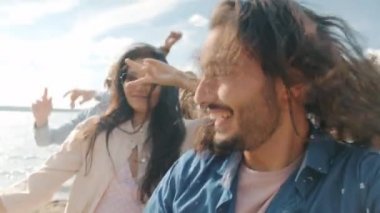Sahilde dans eden neşeli Orta Doğulu adam yaz günü arkadaşlarıyla eğleniyor.