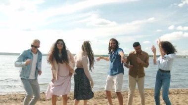 Göl kıyısında dans eden kadın ve erkeklerin ağır çekimde güzel bir eş zamanlı tatil boyunca eğlenmeleri.