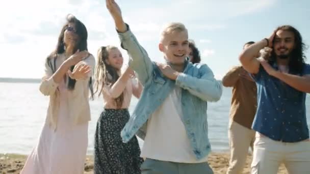 Muotokuva iloinen tyttöjen ja poikien ystäviä tanssia ja pelleillä ulkona rannalla — kuvapankkivideo