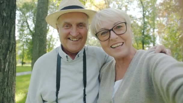 Portrait POV de couples joyeux de personnes âgées faisant un appel vidéo en ligne depuis le parc regardant la caméra — Video