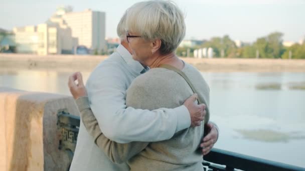 Ouderen getrouwd stel ontmoeten elkaar in de stad straat knuffelen uiten liefde aan de rivier dijk — Stockvideo