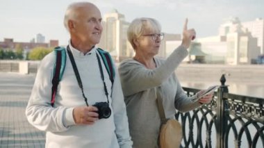 Üst düzey turistler, ellerinde harita ve kamerayla yürüyen ve gülen bir çiftle evlendi.