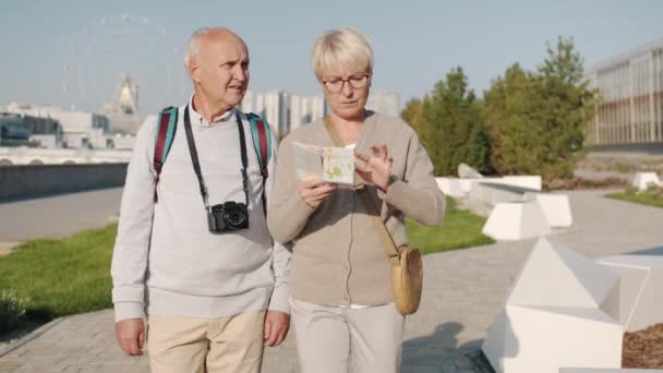 Dolly shot van gelukkige paar toeristen wandelen in de stad op zoek naar kaart en rond te wijzen genieten van reis — Stockvideo