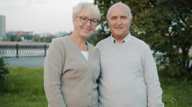 Yaz günü şehirde dikilen yaşlı bir çiftin ağır çekimde portresi.