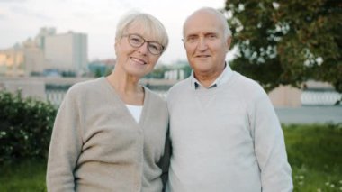 Şehir sokağında gülümseyen yaşlı bir çiftin portresi.