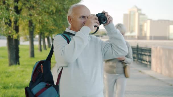 Старший чоловік і жінка туристи фотографують сучасне місто і дивляться на карту на відкритому повітрі в літній день — стокове відео