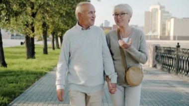 Güzel şehirde yürüyen yaşlı çiftler yaz günü manzaranın tadını çıkarıyorlar.