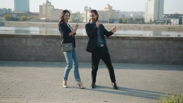 Blandad ras man och kvinna dansar utomhus leende lurar runt mot urban bakgrund — Stockvideo