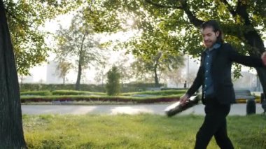 Şehrin sokaklarında yürüyen neşeli melez bir adamın evrak çantasını fırlatıp yaz gününün tadını çıkarırken yan görüntüsü.