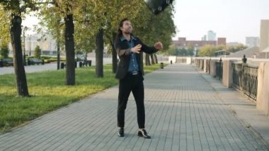 İyi görünümlü genç işadamının yazın dışarı attığı ve yakaladığı evrak çantasının resmi.