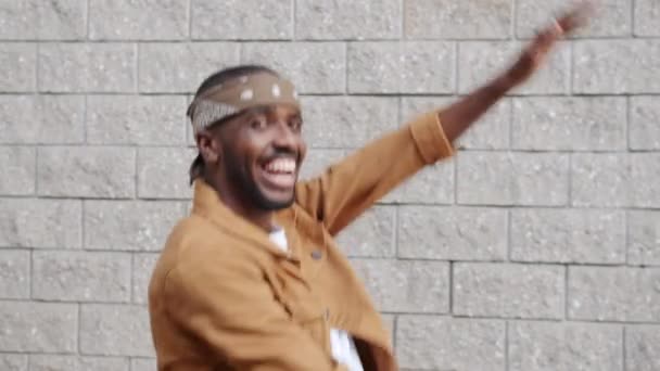 Portrait of cheerful African American person dancing gesturing outside on wall background — Stok Video