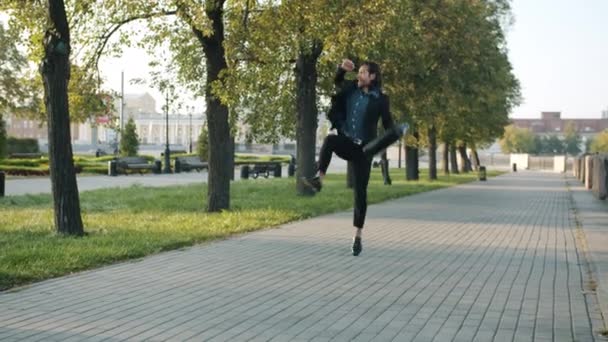 Framgångsrik ung affärsman promenader i staden med resväska sedan hoppa och dansa — Stockvideo