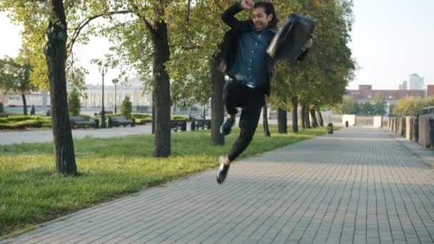 Бесконечный цикл возбужденного молодого бизнесмена, идущего и прыгающего по городской улице, выражая радость — стоковое видео