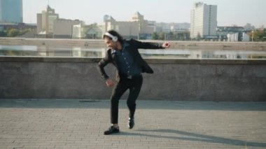 Nehir kenarında eğlenen, kulaklık takan neşeli, melez bir ırkın dans döngüsü.