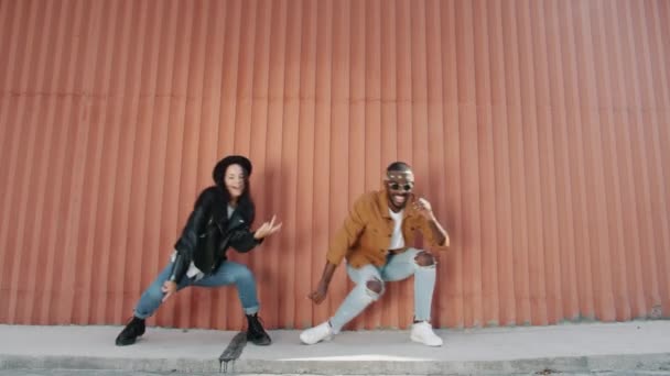 Afro-American guy and mixed race girl dancing outdoors together on wall background — Stock Video
