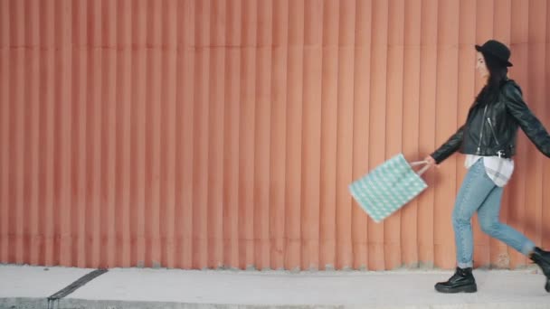 Медленное движение молодой женщины, идущей с мешками для покупок, разворачиваясь, выражая счастье — стоковое видео