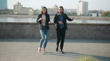 Mutlu kız ve erkek dışarıda dans ediyor, gülüp eğleniyorlar, şehirde yaz gününün tadını çıkarıyorlar.